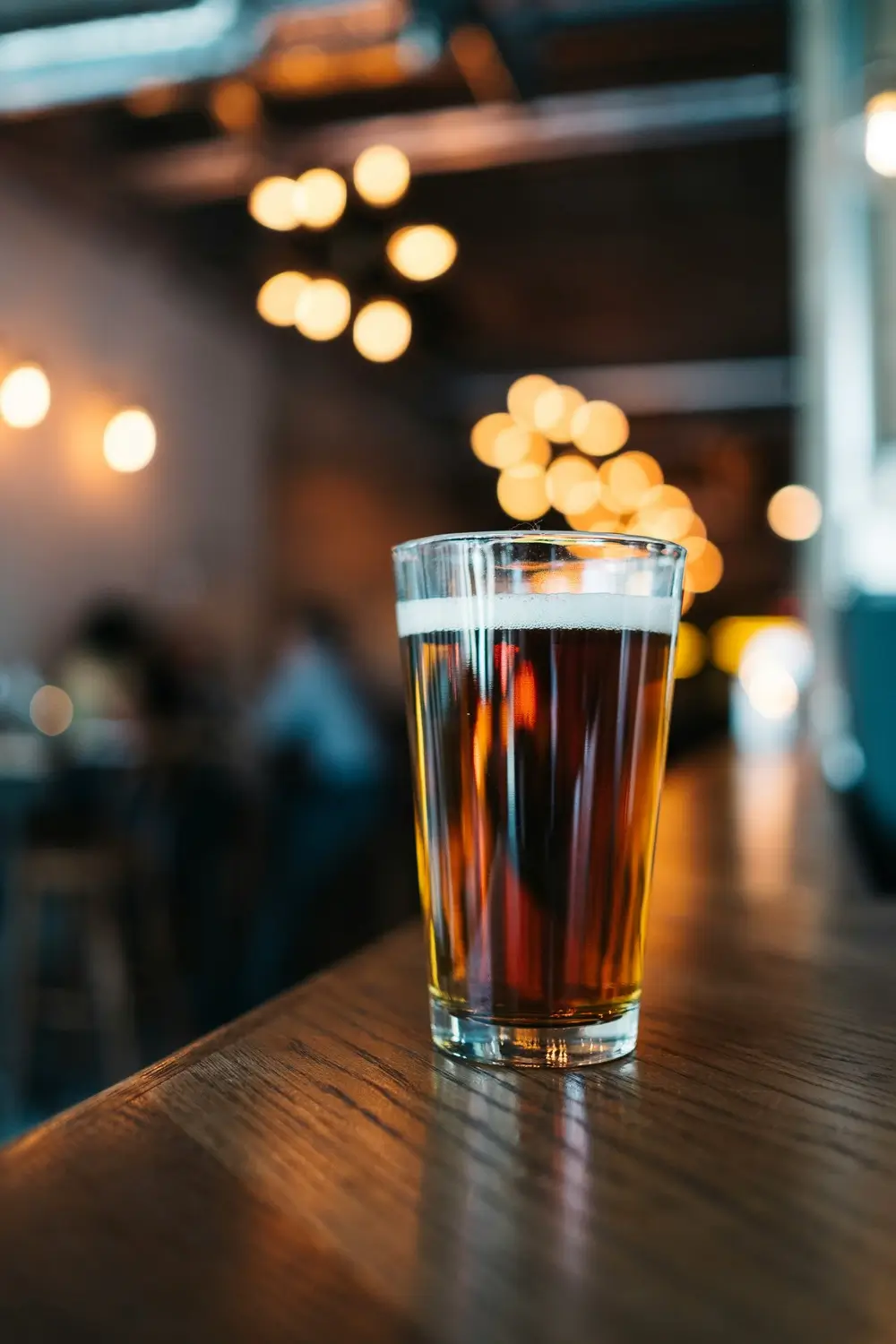 Picture of a beer glass on a table in a bar with beautiful background lights