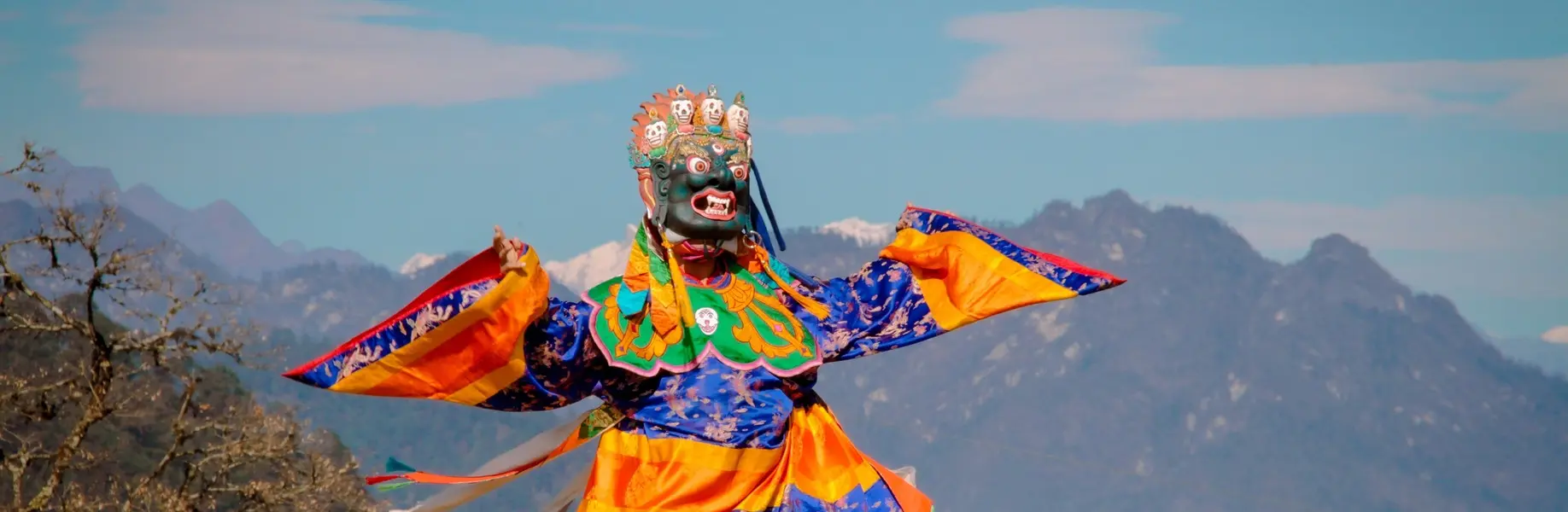Sacred mask dancers in vibrant costumes performing Cham at a Bhutan Tshechu festival