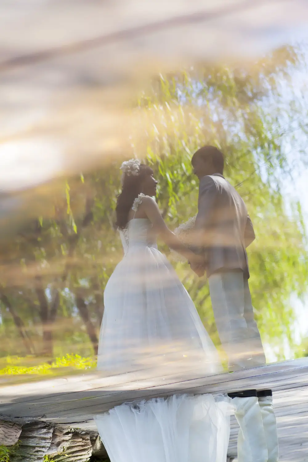 Picture of a couple dressed in wedding gowns holding hands and looking at each other